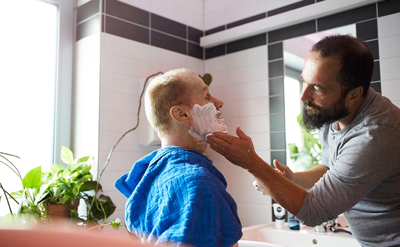 Ein Betreuer hilft einem Bewohner beim rasieren.