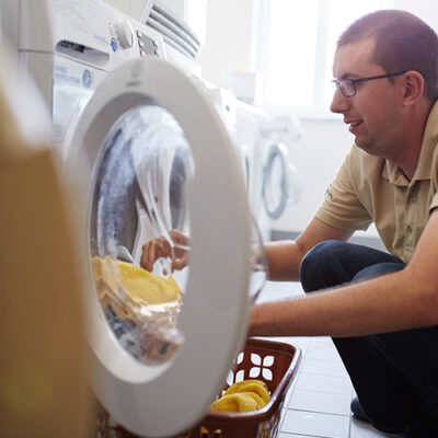 Ein Mann füllt die Waschmaschine mit Handtüchern.