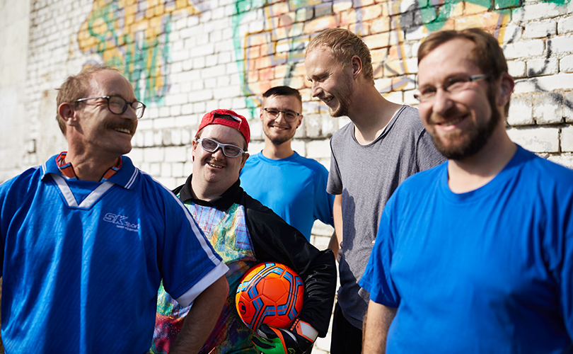 Eine Gruppe Jungs hat blaue Sportsachen an. Der Torwart hält einen Fußball in der Hand.