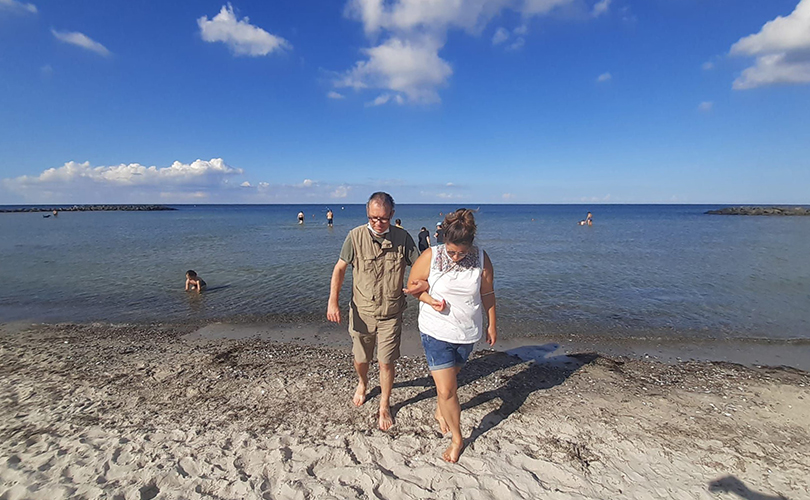 Zwei Personen laufen eingeharkt am Meer.