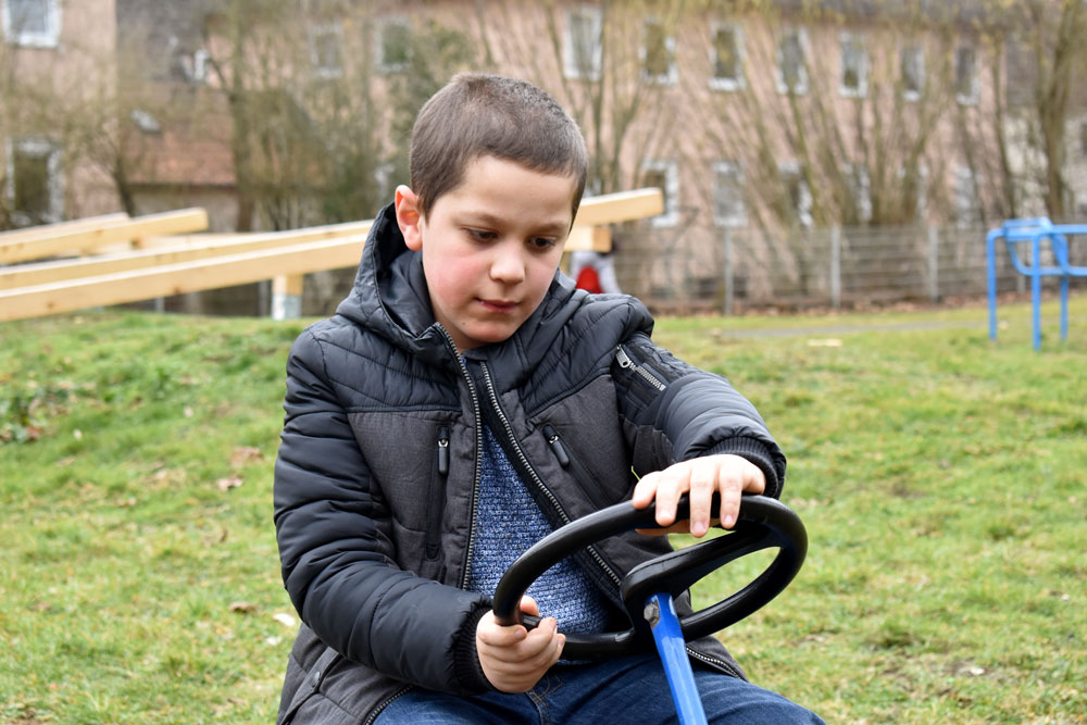 Ein Junge sitzt auf einem Ketcar und hält das Lenkrad in der Hand